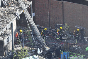 Firefighters walk through debris outside Grenfell Tower