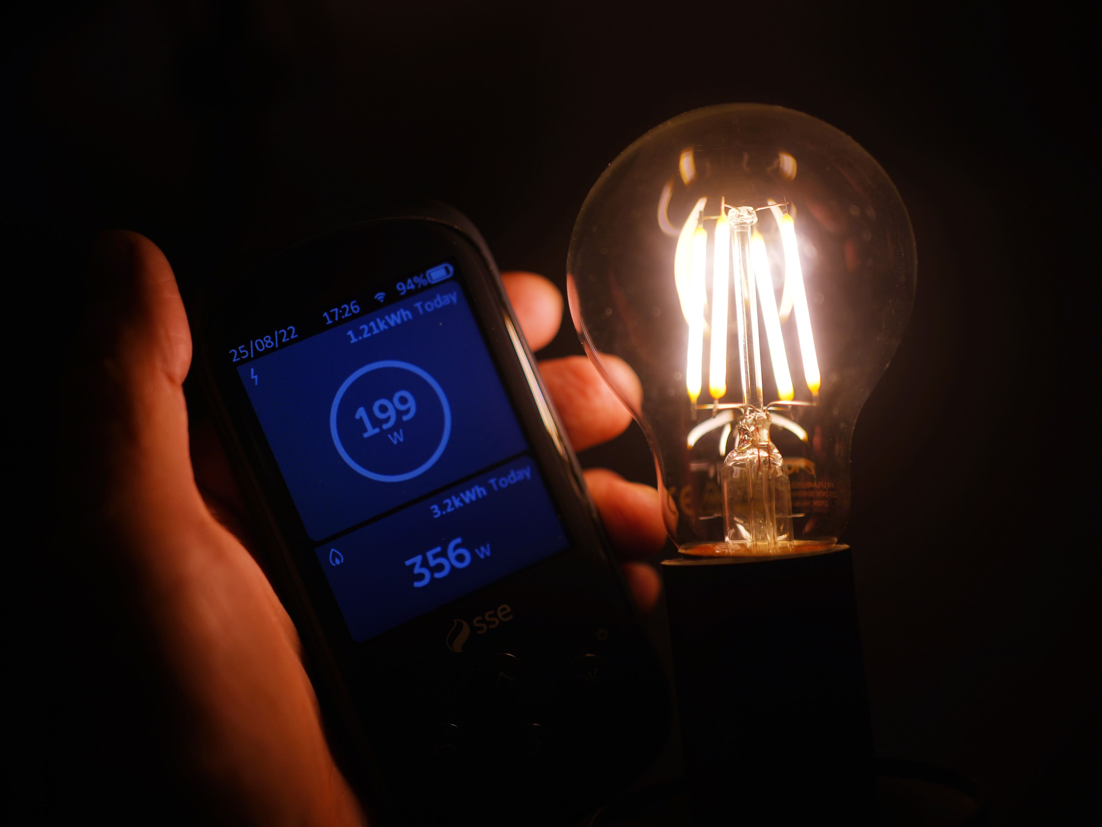 A general view of a smart meter app next to a lightbulb against a dark background