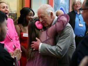 The King getting a hug from Florence McGrellis during a visit to Cartwright Hall in Bradford