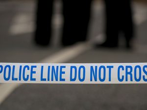 Tape reading 'police line do not cross' stretched over a road