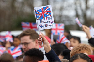 A schoolchild from Fibbersley Park Primary Academy waves a Union flag with "Hello Prince William" written on it 