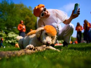 A woman poses with Lucy, a dog whose fur has been dyed orange, as people celebrate King’s Day in Amsterdam, Netherlands