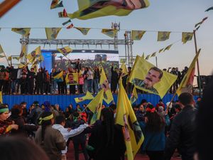 Kurdish residents hold flags showing Abdullah Ocalan