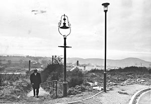 The Delph, Brierley Hill, November 1979. 'Side by side stand the old and the new...the "ancient" ornamental gas lamp and the sleek, highly practical modern electric light....Old Bill Wood (pictured), a former miner of these parts, seen on the steps, remembers well those shifts of darkness, but they are just stories to the new generation.'