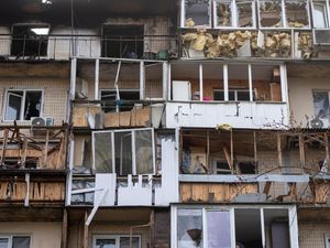 A resident cleans up the damaged apartment in a multi-storey house after Russia’s night drone attack, in Kyiv, Ukraine