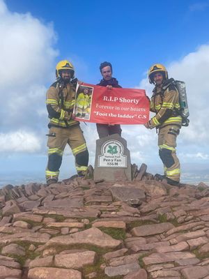 Firefighters Aidan Wolvers and Matt Pardy unfurled a banner in tribute to colleague Chris Short, who died recently aged 42