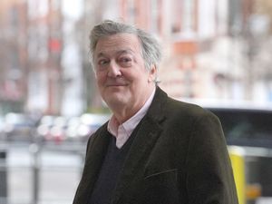 Sir Stephen Fry smiles at photographers