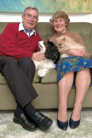 The couple with their pet dog and cat at home
