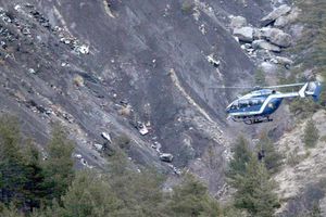A rescue helicopter flies in front of debris from the crash