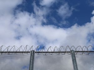 A prison fence with blue sky above