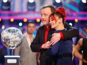 Dianne Buswell and Chris McCausland hug beside the glitterball trophy