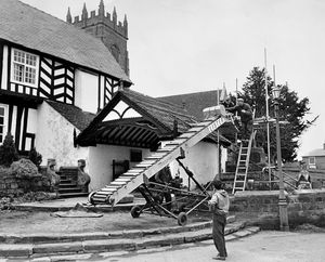 February 16, 1965 - the caption reads: 'The old Butter Cross at Claverley is under renovation by a Bridgnorth firm of stonemasons. Only one new piece of stone is being used, the rest is reclaimed from the surrounds. This type of stone originally quarried at Alveley is no longer available. An agricultural conveyor was being used yesterday to take the pieces of masonry to the top.'