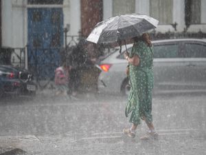 A person walks in the rain through in Kentish Town, north London