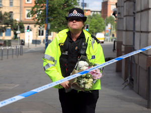 A police officer moves a floral tribute close to the Manchester Arena