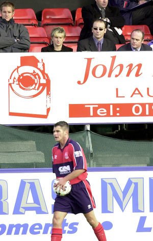 Andy Shaw, in sunglasses, watches from the directors' box as defender Ashley Wooliscroft prepares to take a thrown-in in the October 2001 FA Cup encounter against Northwich.