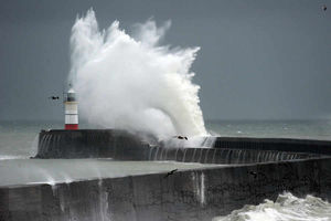 Waves crash into a lighthouse in East Sussex