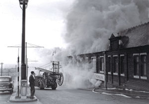 Smoke bellowing out of the machine shop as the fire engine arrives at Hillmans Leather Works, Dudley in April 1958.