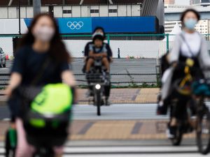 Women carry children on their bikes as they ride through an intersection in Tokyo