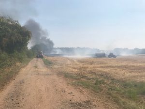 Tractors pour water over the field to help contain the fire. 