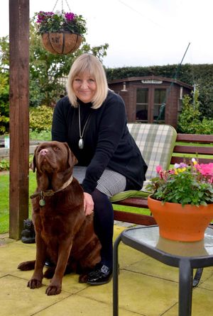 Ann Hartley in her garden with Mocha her chocolate labrador